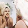 skin care concept. young happy woman in towel making facial mass
