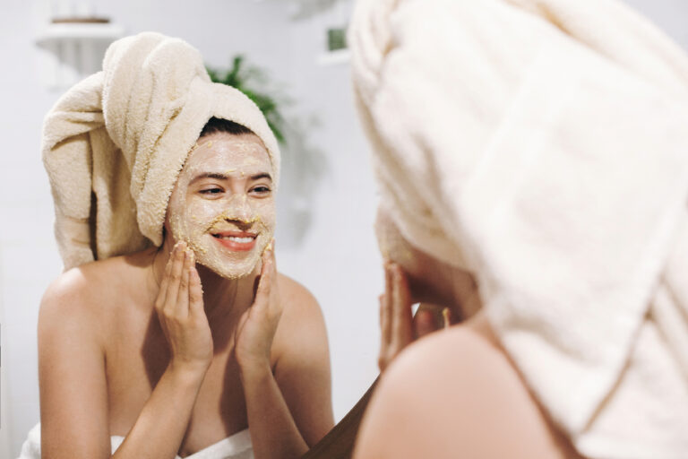 skin care concept. young happy woman in towel making facial mass