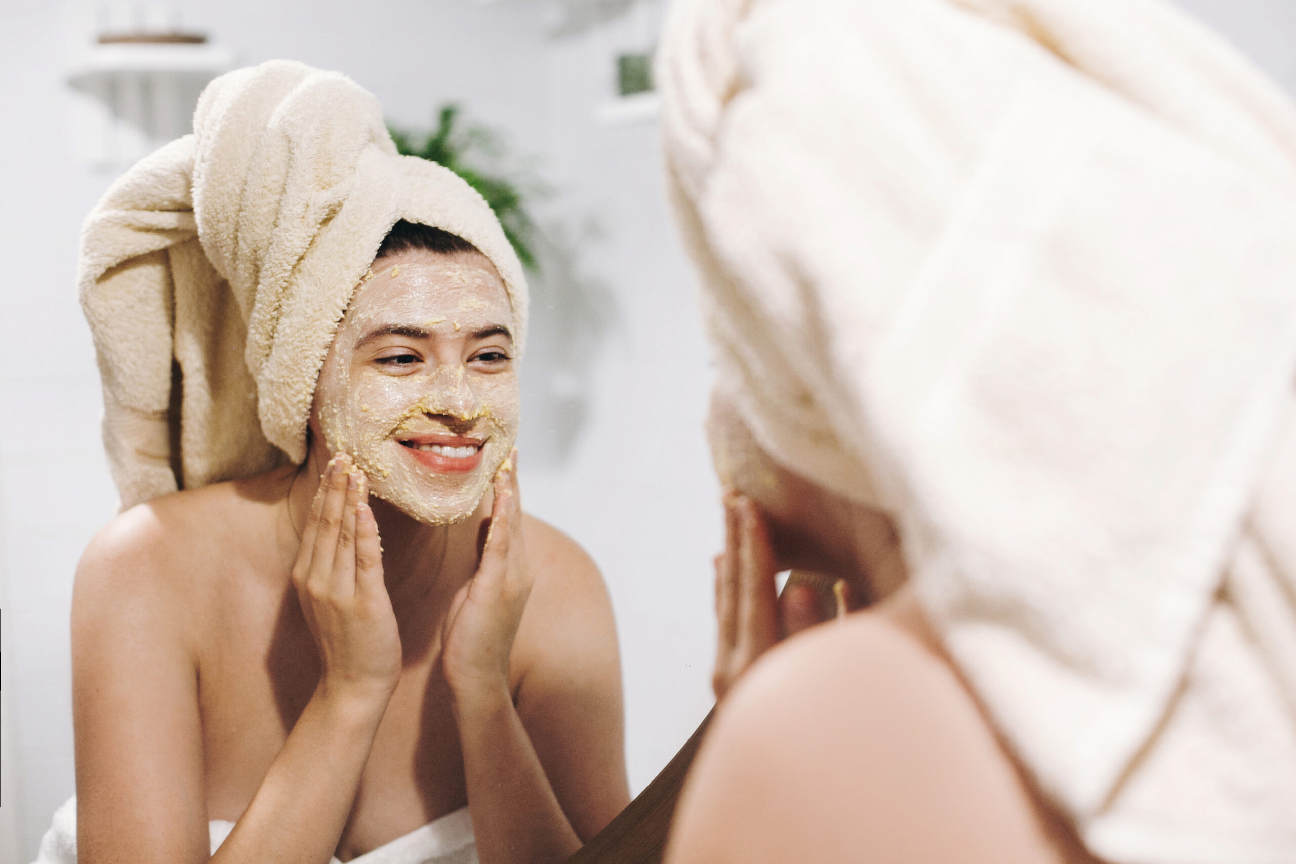 skin care concept. young happy woman in towel making facial mass