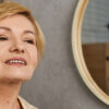 in a calm indoor space, a lovely senior woman smiles as she enjoys her skincare routine.