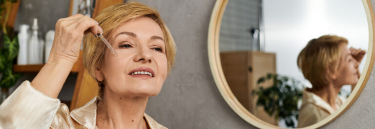 in a calm indoor space, a lovely senior woman smiles as she enjoys her skincare routine.