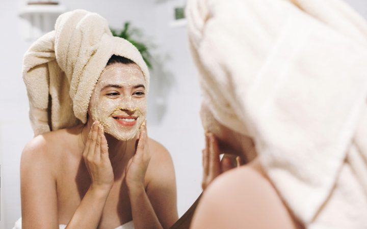 skin care concept. young happy woman in towel making facial mass