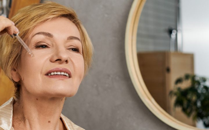 in a calm indoor space, a lovely senior woman smiles as she enjoys her skincare routine.